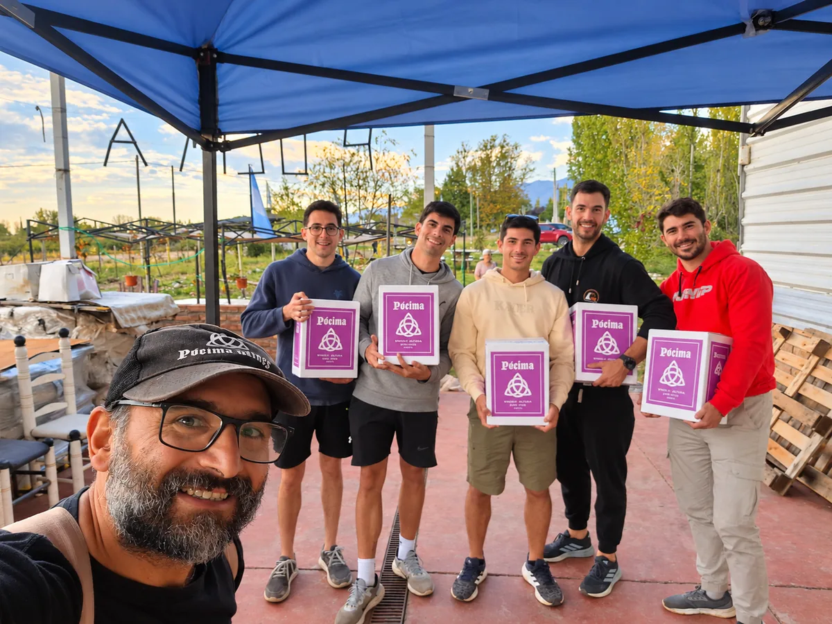 Cinco visitantes con cajas de vino Pócima en la bodega