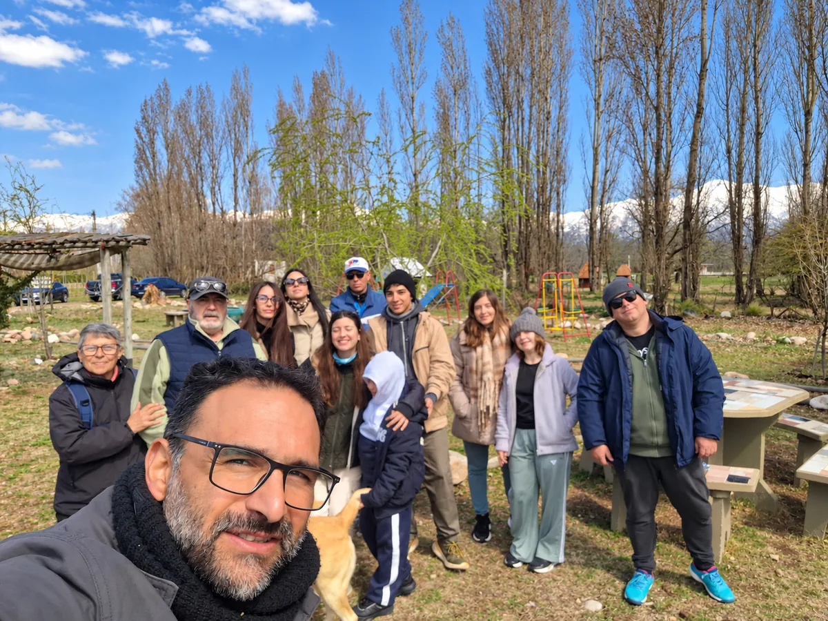 Un grupo de visitantes en la arboleda, con la cordillera nevada de fondo